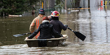 Trabajadores de rescate remando un bote que avanza por las inundaciones 