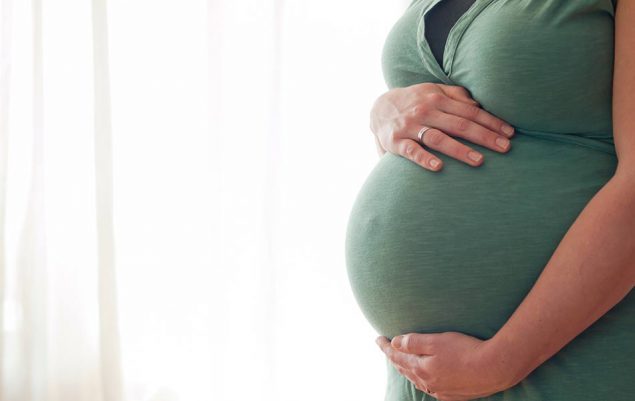 Image of pregnant woman cradling her midsection with both hands