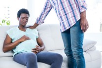 Pregnant woman looking distressed as her partner comforts her